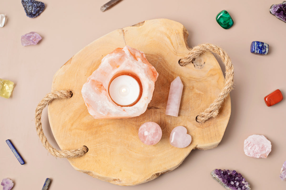 All products collection banner for The Tiny Topaz showing a variety of colourful crystals surrounding a Himalyan candle and Rose Quartz heart, sphere and tower crystals on a wooden board.