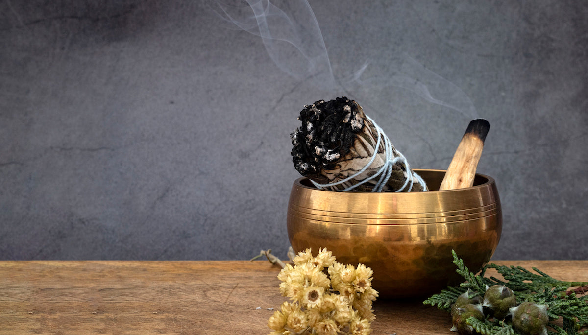 Smudge and incense collection banner for The Tiny Topaz showing a sage smudge and a palo santo stick in a copper bowl, still slightly smoking.