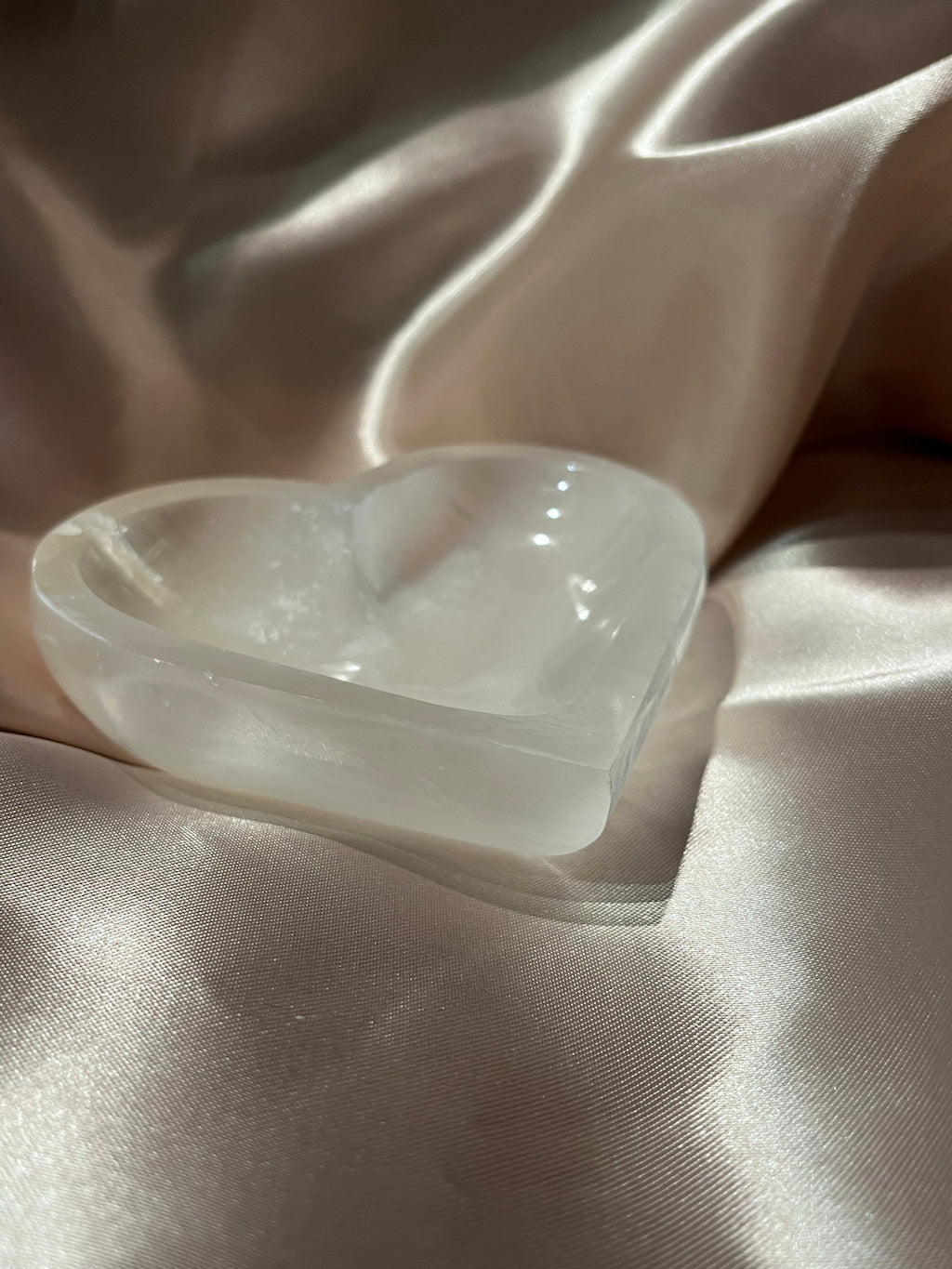 Selenite heart shaped bowl on a bronze background.