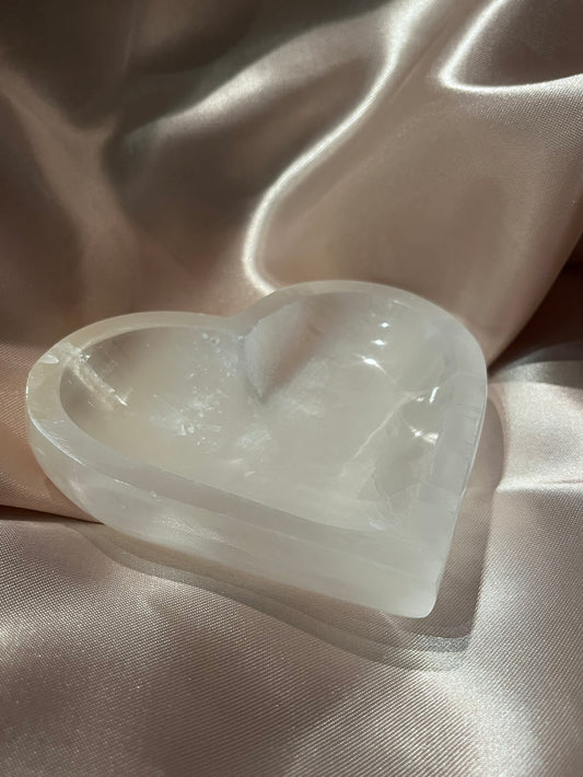 Selenite heart shaped bowl on a bronze background.